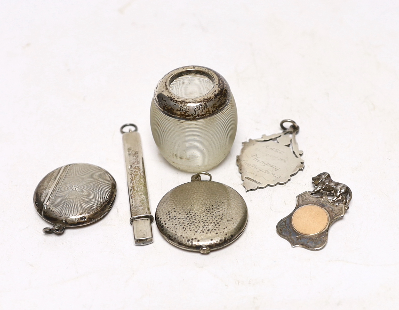 An early 20th century silver mounted ribbed glass match strike, 47mm and five other items including a silver vesta case, white metal locket, two medallions and a pencil.